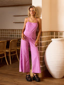 Woman in a pink jumpsuit standing in a room with tiled walls and wooden flooring.